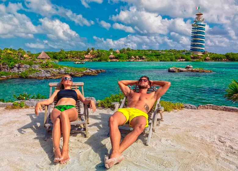 Couple sunbathing in the bay of XelHa park with its water slide in the background